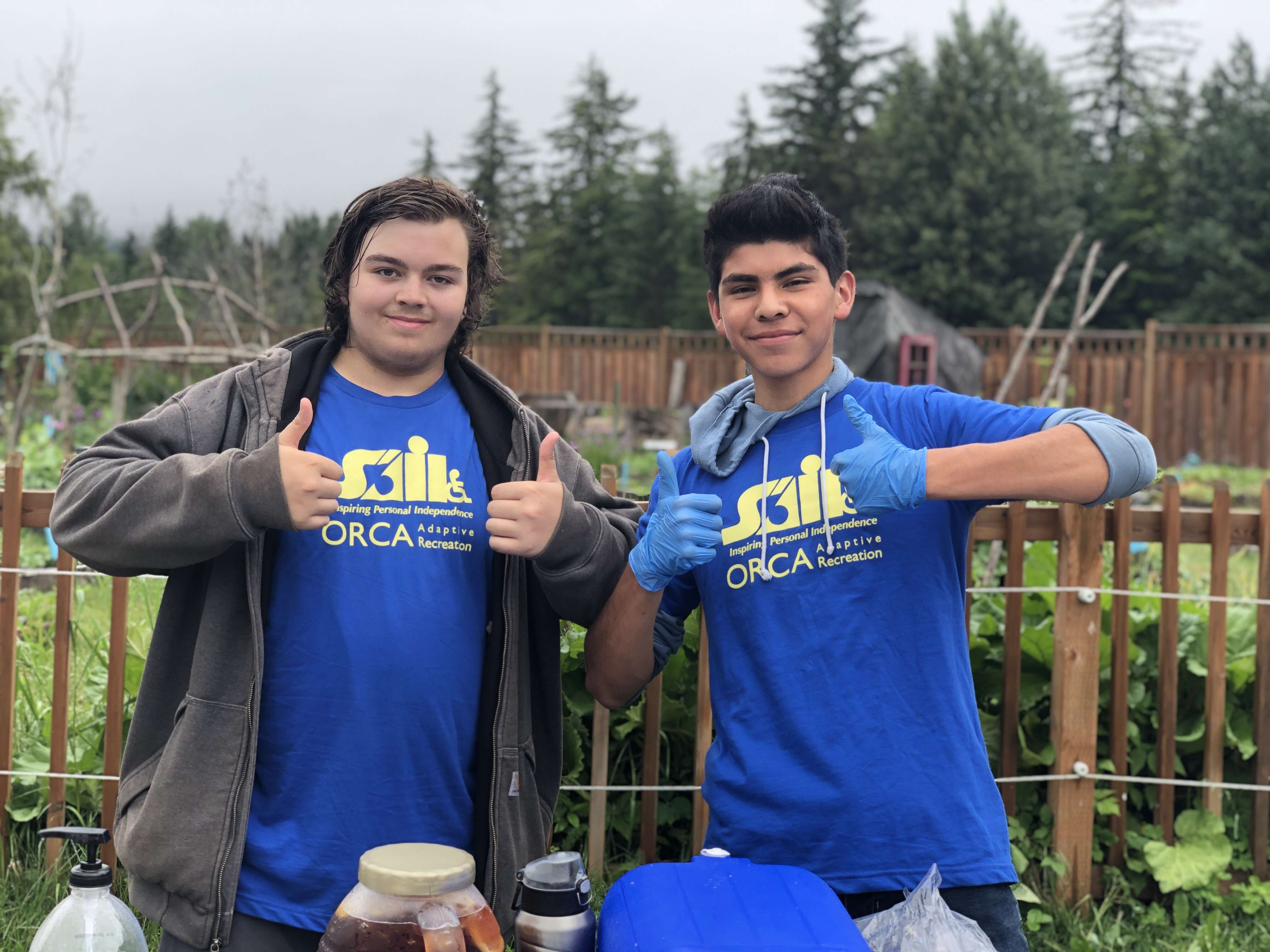 two young men wearing blue SAIL shirts posing with their thumbs up