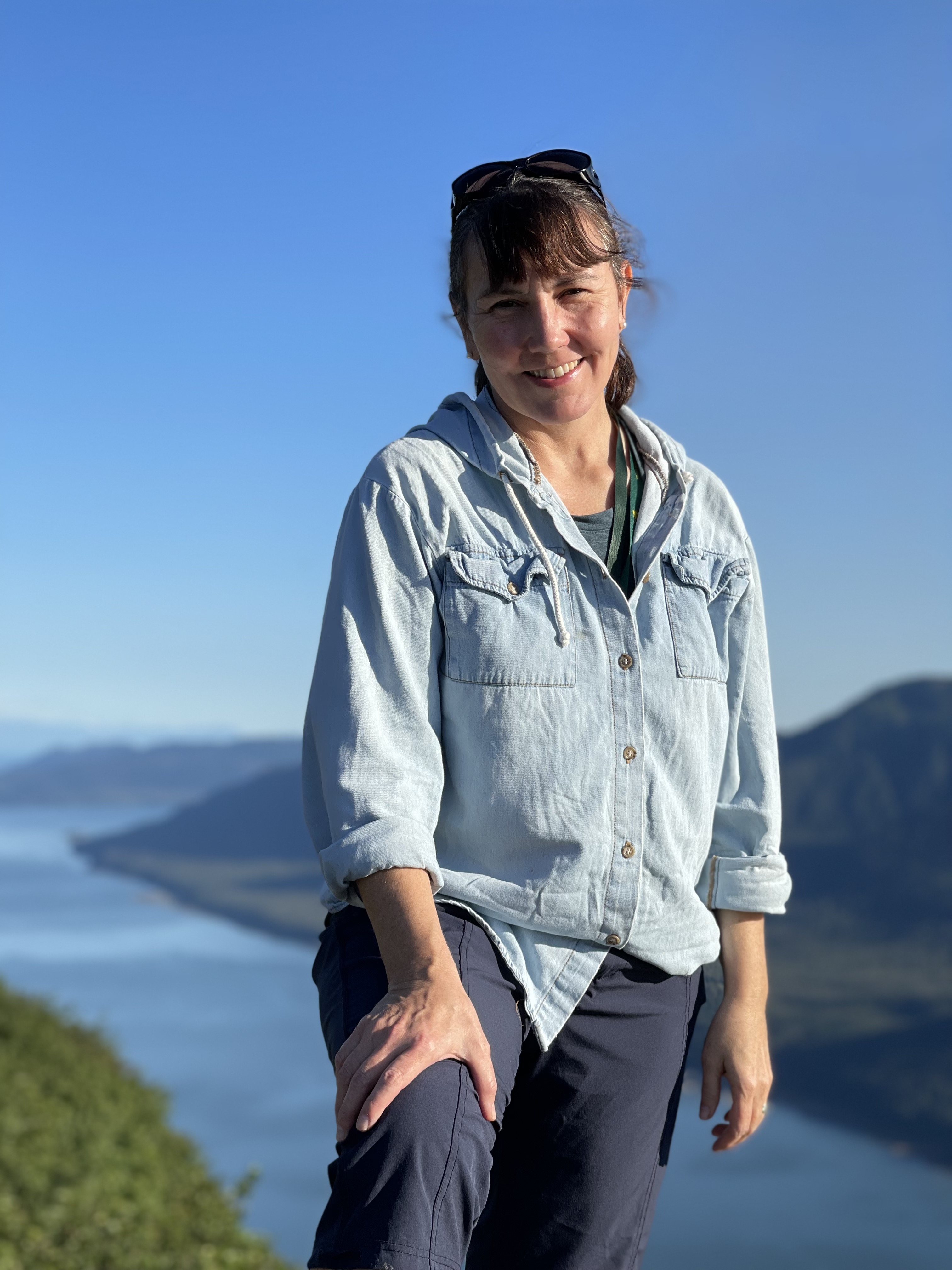 photo of linda standing on top of mountain with clear blue sky in the background